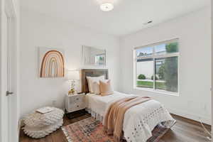 Spacious bedroom with vinyl floors and a large window.