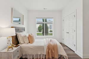 Spacious bedroom with vinyl floors and a large window.