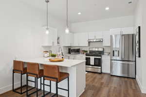 Kitchen with a counter-level peninsula, quartz countertops, stainless steel appliances, a breakfast bar and hanging light fixtures