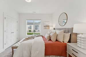 The main bedroom has a large window that frames the green grass and lets in light.