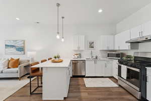 Kitchen with counter level peninsula, quartz countertops, stainless steel appliances, a breakfast bar and hanging light fixtures