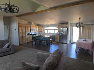 Living room with a chandelier, a textured ceiling, dark wood finished floors, and dark colored carpet