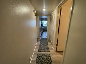Hallway featuring light wood finished floors and a textured wall