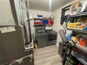 Laundry area featuring heating unit, light wood-style floors, and washer and dryer
