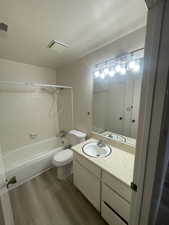 Full bath featuring vanity, washtub / shower combination, and dark wood-type flooring