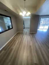 Unfurnished dining area with wood finished floors, a chandelier, and a textured ceiling
