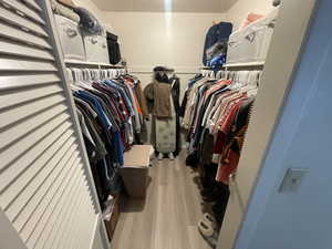 Walk in closet with light wood finished floors