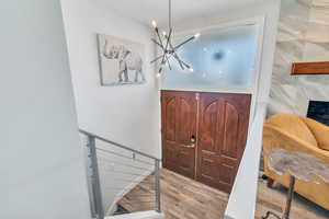 Foyer entrance with light wood-style floors, stairs, and a chandelier
