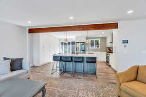 Kitchen with open floor plan, white cabinetry, a breakfast bar, a center island with sink, and recessed lighting