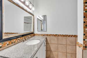 Bathroom with tile walls, vanity, and wainscoting