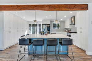 Kitchen featuring pendant lighting, stainless steel appliances, white cabinets, a breakfast bar area, and a large island