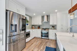 Kitchen featuring appliances with stainless steel finishes, pendant lighting, white cabinets, light stone counters, and recessed lighting