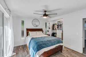 Bedroom with wood finished floors, ceiling fan, and a spacious closet