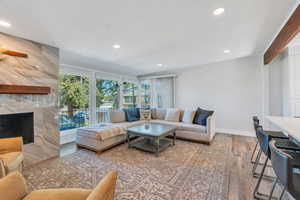 Living area with a premium fireplace, wood finished floors, recessed lighting, and beamed ceiling