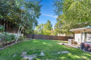 Fenced backyard featuring a hot tub