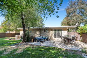 Rear view of property with an outdoor living space with a fire pit, a fenced backyard, brick siding, and a patio area