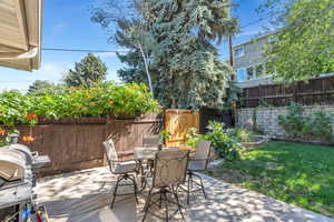 Fenced backyard with a grill, outdoor dining area, and a patio