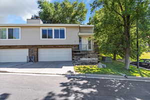 View of front of house with a garage, concrete driveway, a chimney, and stone siding