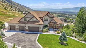 Craftsman house with driveway, stone siding, a garage, a mountain view, and a front yard