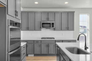 Kitchen featuring stainless steel appliances, tasteful backsplash, light wood finished floors, light stone countertops, and recessed lighting