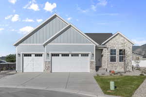 Craftsman house with stone siding, driveway, board and batten siding, and a garage