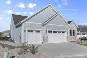 View of front of house with concrete driveway, stone siding, and a garage