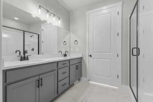 Full bath featuring double vanity, a stall shower, and light marble finish floors