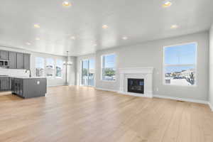 Unfurnished living room with recessed lighting, light wood finished floors, a glass covered fireplace, and a chandelier