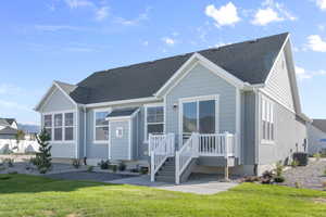 View of front of home with a front lawn, roof with shingles, and a deck