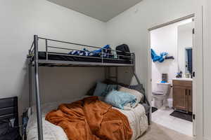 Bedroom with tile patterned floors, ensuite bathroom, and a textured ceiling