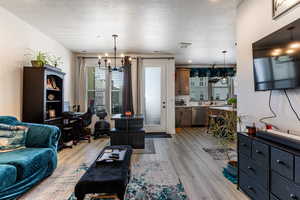 Office space with a textured ceiling, a chandelier, and light wood-style floors