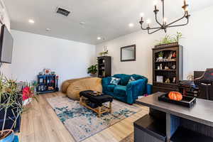 Living area with a chandelier, a textured ceiling, light wood-style flooring, and recessed lighting