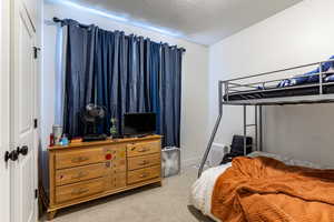 Bedroom with light colored carpet and a textured ceiling