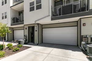 View of front of property with a garage, a balcony, driveway, and stucco siding