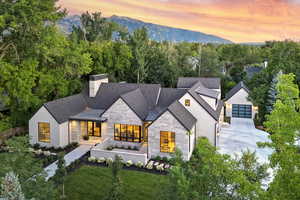 View of front of home featuring stone siding, a chimney, driveway, a mountain view, and stucco siding