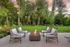 Patio terrace at dusk with a patio, a lawn, and an outdoor fire pit