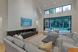 Living area featuring high vaulted ceiling, light wood-type flooring, and a fireplace