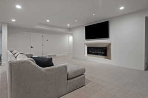 Living area featuring recessed lighting, light carpet, and a glass covered fireplace