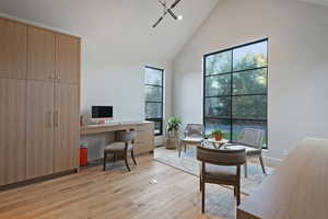 Office space with high vaulted ceiling and light wood-type flooring