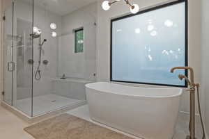 Bathroom featuring a chandelier, a freestanding bath, a shower stall, and tile patterned floors