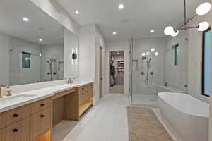 Bathroom featuring a spacious closet, double vanity, a shower stall, a freestanding tub, and recessed lighting