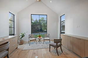 Living area with light wood-style floors and high vaulted ceiling