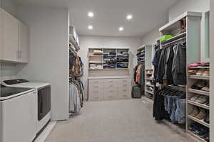 Walk in closet featuring light colored carpet and washing machine and dryer