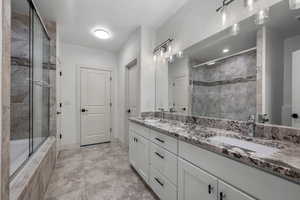 Full bath with double vanity, light tile patterned floors, and tiled shower / bath combo