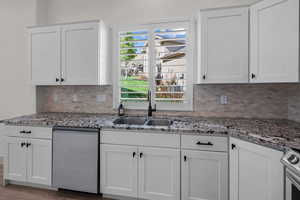 Kitchen featuring white cabinets, stainless steel appliances, light stone countertops, and decorative backsplash