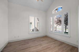 Spare room featuring vaulted ceiling and light wood-style floors
