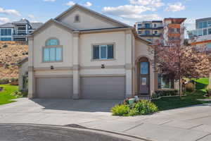 View of front facade featuring an attached garage, stucco siding, driveway, and a front lawn