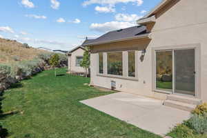 Rear view of property featuring stucco siding, a yard, a patio, and roof with shingles