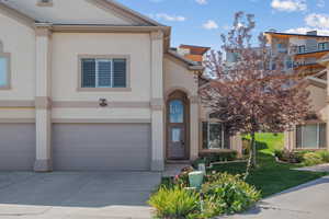 View of front of home featuring an attached garage, stucco siding, driveway, and a front yard