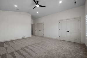 Unfurnished bedroom featuring multiple closets, carpet flooring, vaulted ceiling, a ceiling fan, and recessed lighting